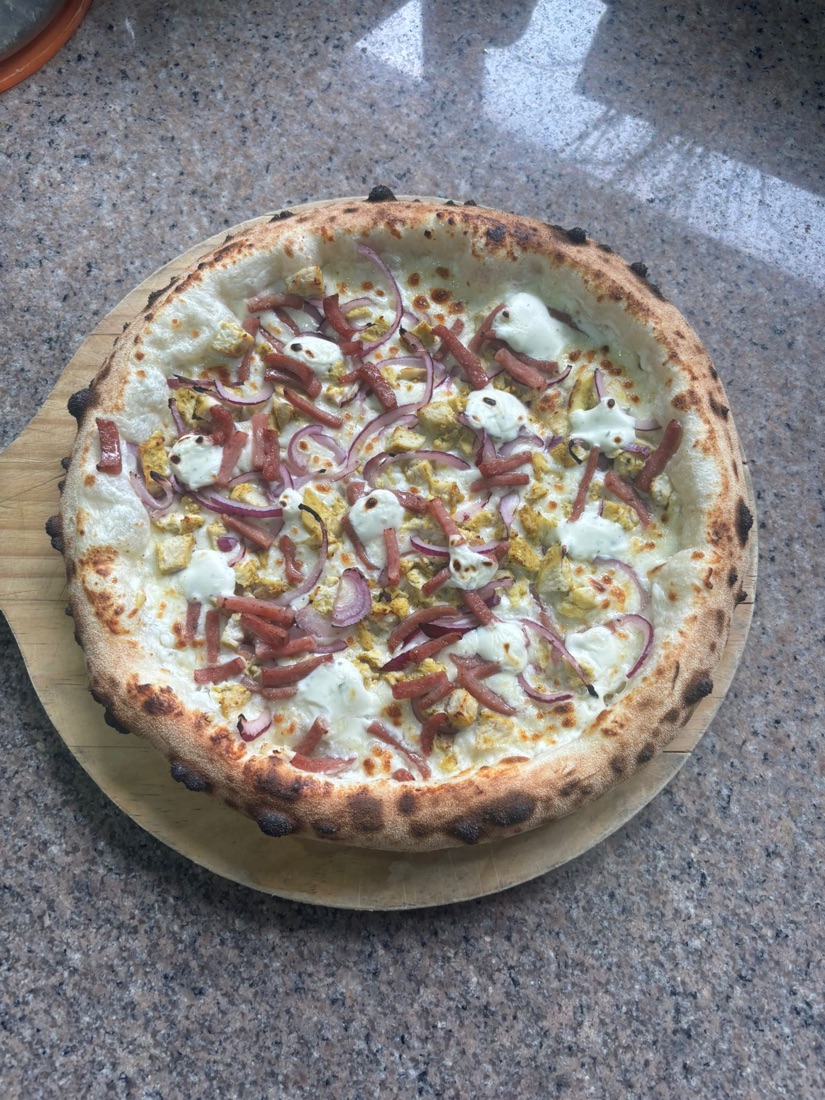 Pizza Ila sur base crème fraîche, poulet, lardons et oignons rouges, sur sa planche en bois
