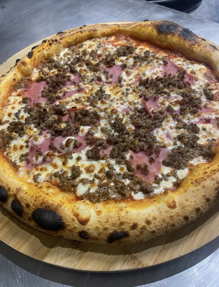 Pizza garnie de viande hachée, jambon et fromage fondu préparée chez Ila Pizza à Brie-Comte-Robert